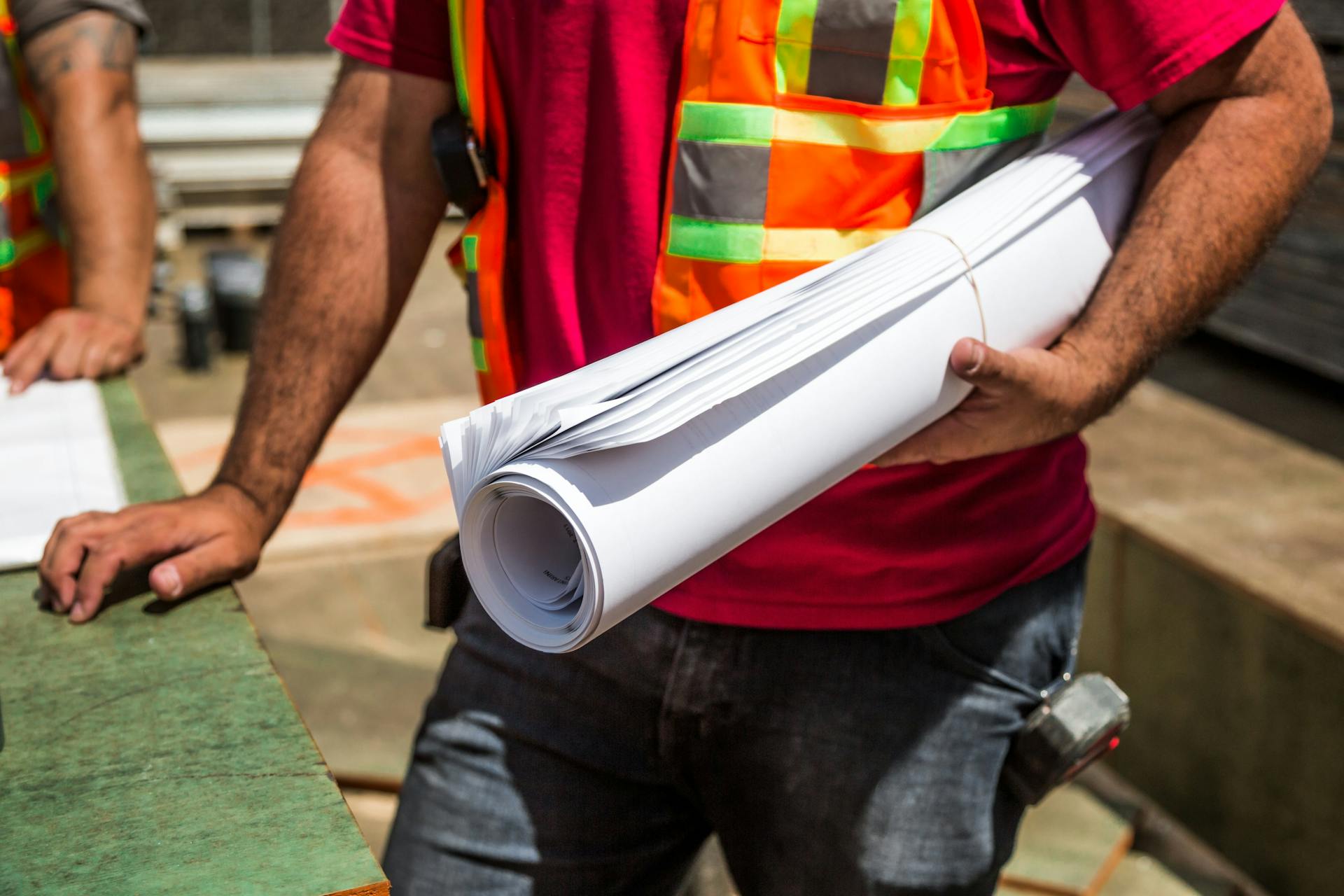 A construction worker holding papers which include an organogram for easy communication in the organisation